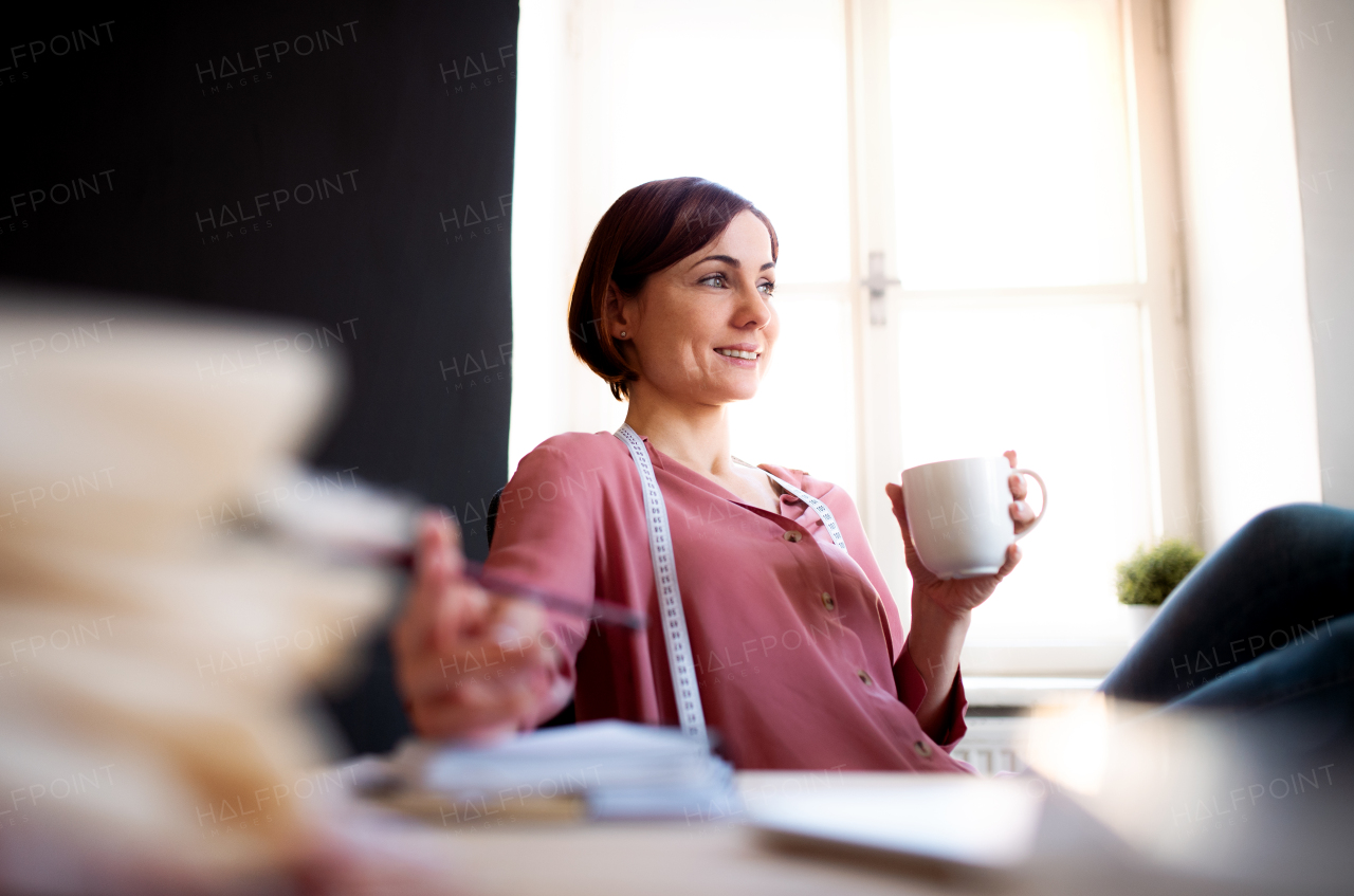 Young creative woman in a studio, resting. A startup of small tailoring business.