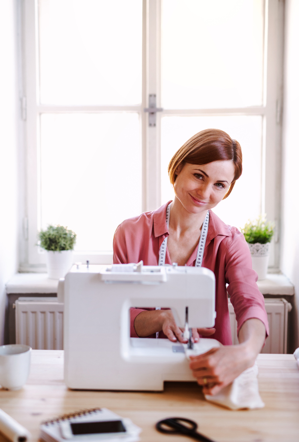 Young creative woman in a studio, working. A startup of small tailoring business.