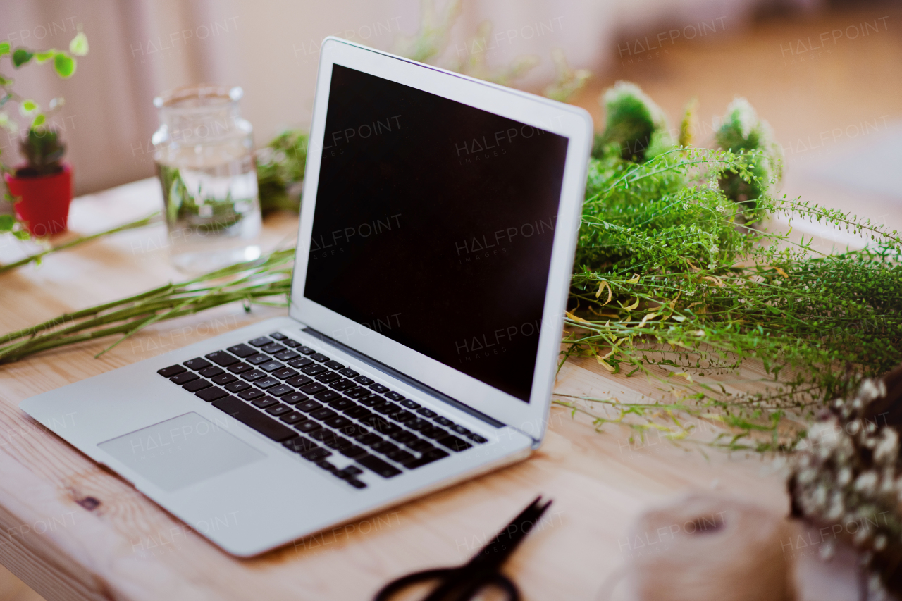 A laptop on desk in a flower shop. A startup of florist business. Copy space.