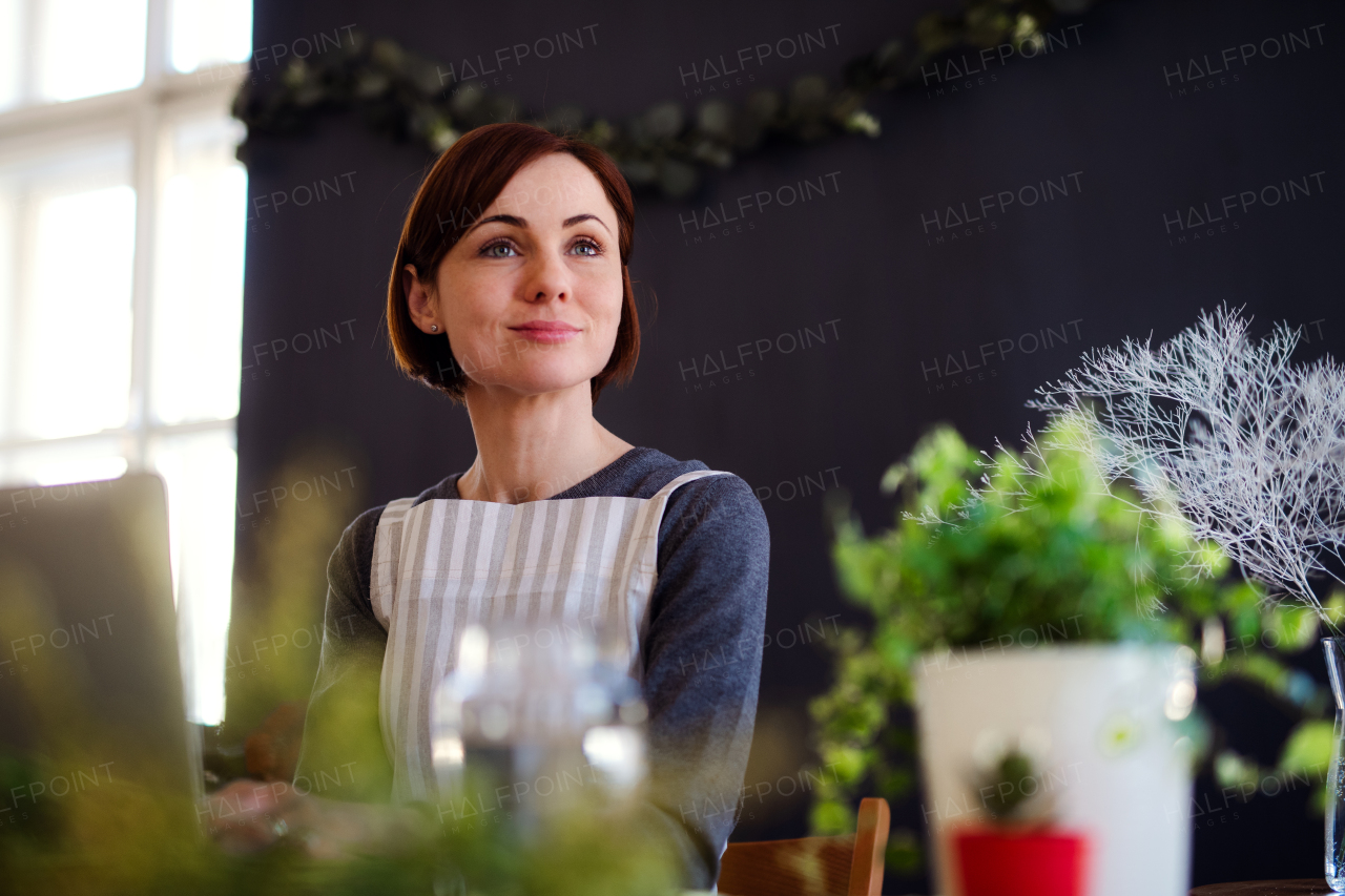 A young creative woman arranging flowers in a flower shop. A startup of florist business.