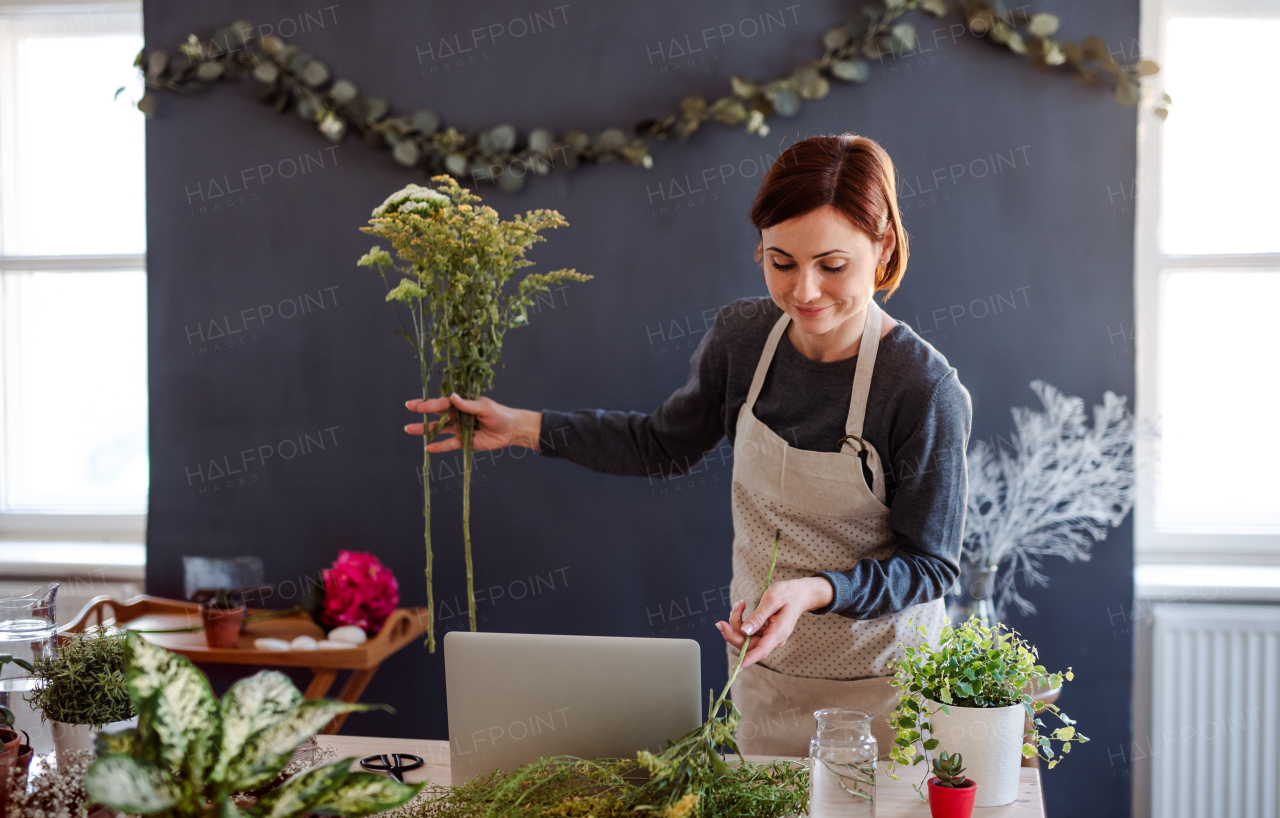 A young creative woman arranging flowers in a flower shop. A startup of florist business.