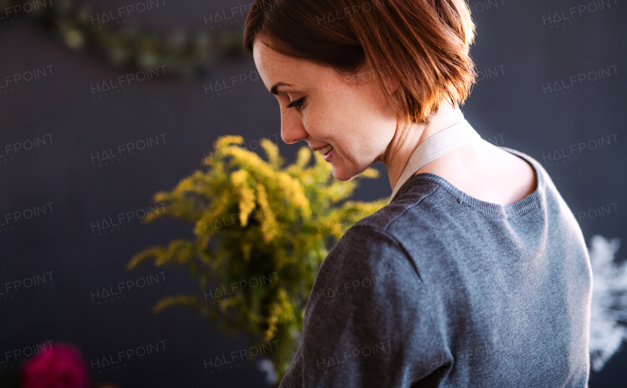 A young creative woman arranging flowers in a flower shop. A startup of florist business.