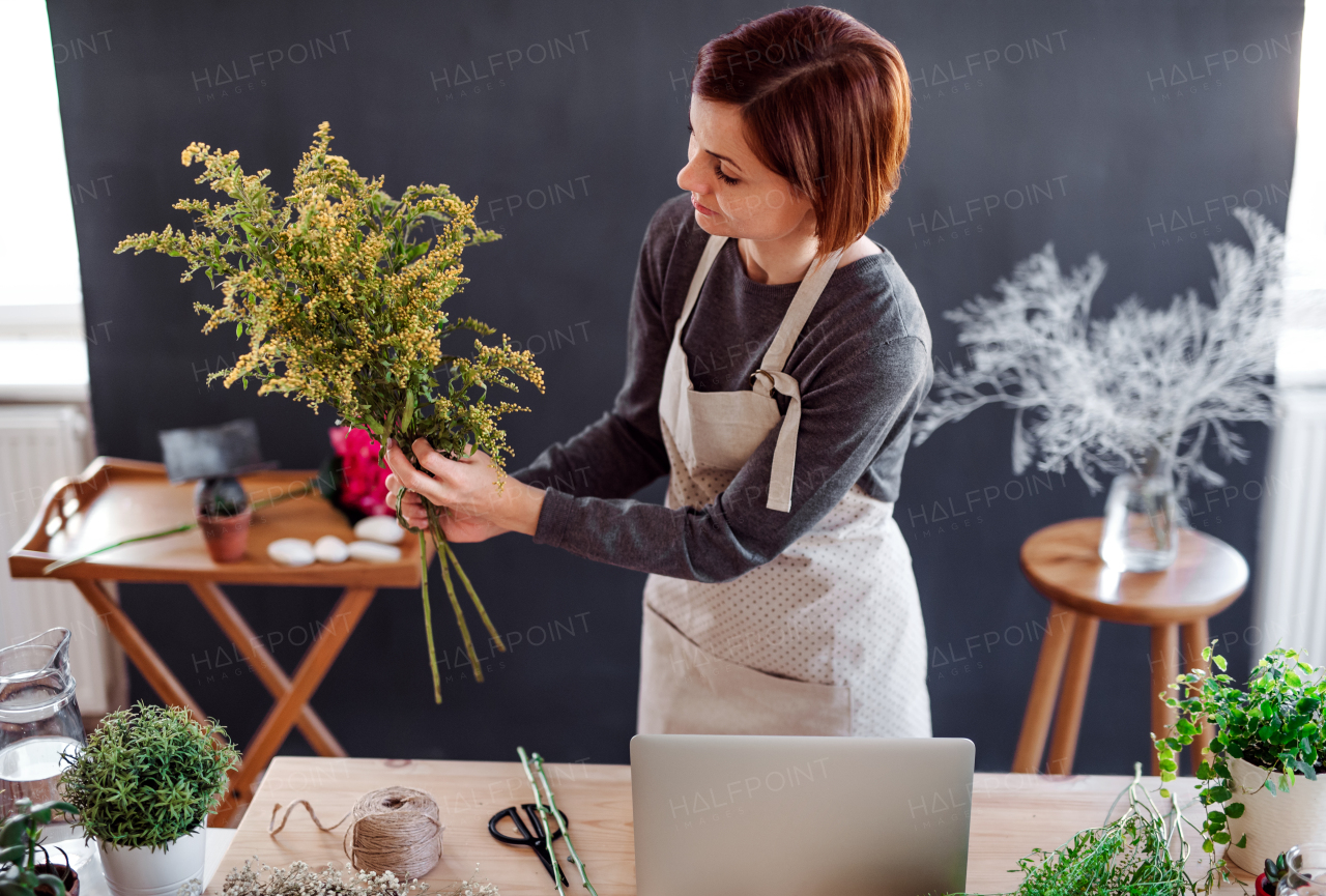 A young creative woman arranging flowers in a flower shop. A startup of florist business.