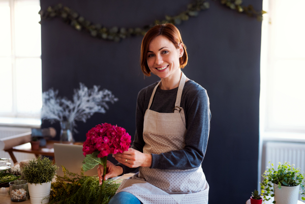 A young creative woman arranging flowers in a flower shop. A startup of florist business.