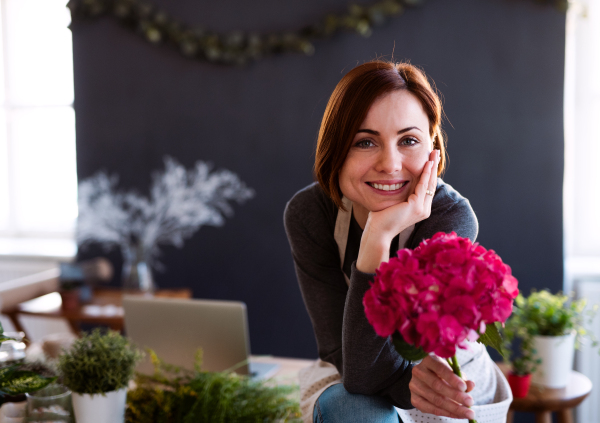 A young creative woman arranging flowers in a flower shop. A startup of florist business.