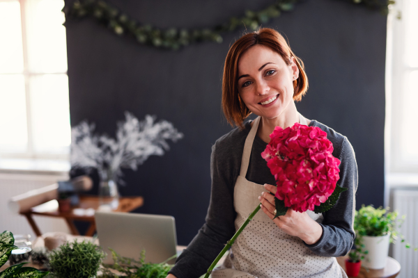 A young creative woman arranging flowers in a flower shop. A startup of florist business.