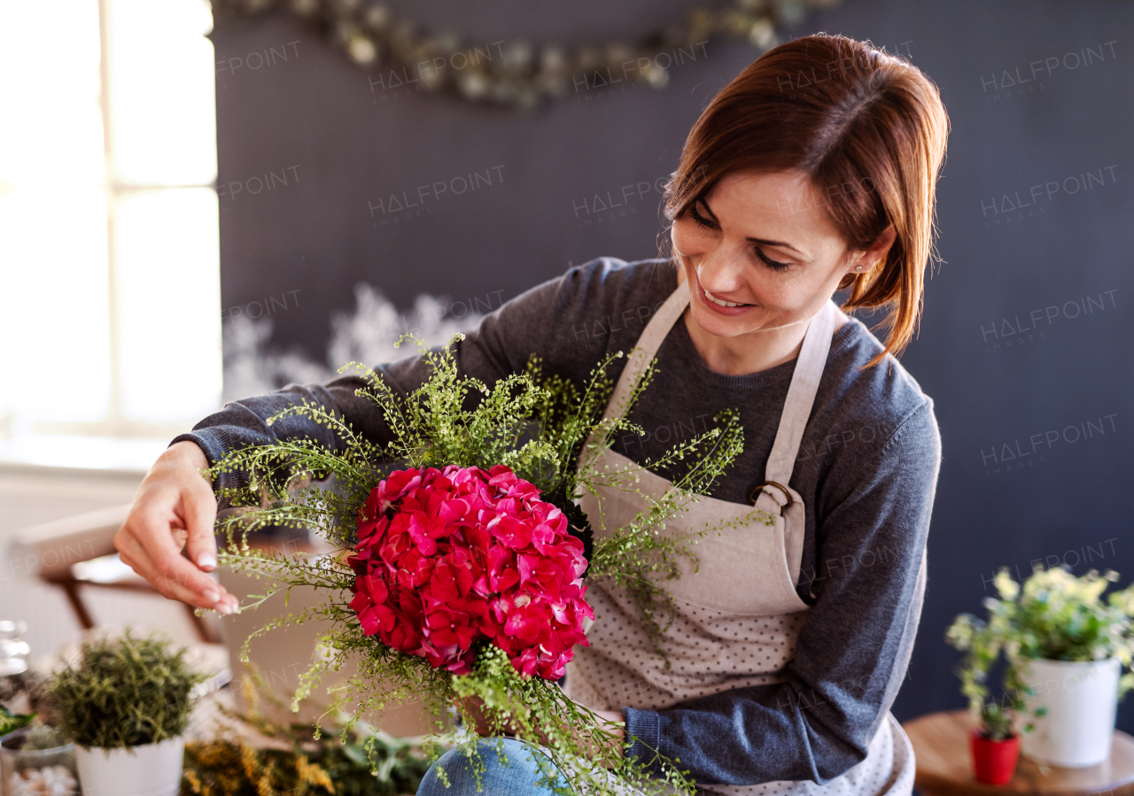 A young creative woman arranging flowers in a flower shop. A startup of florist business.