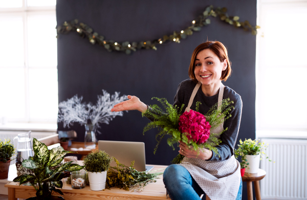 A young creative woman arranging flowers in a flower shop. A startup of florist business.