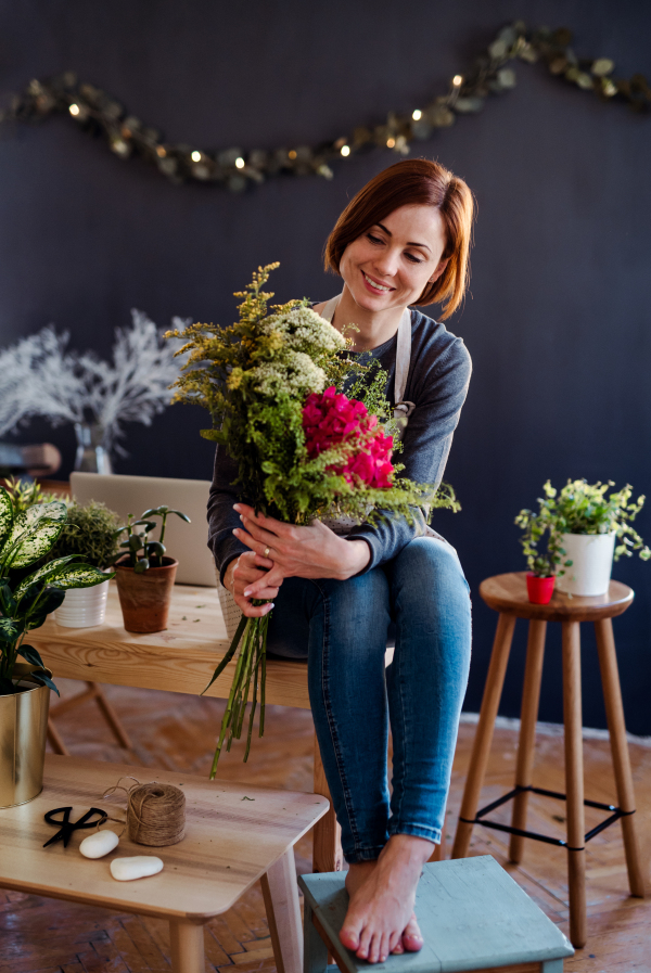 A young creative woman arranging flowers in a flower shop. A startup of florist business.