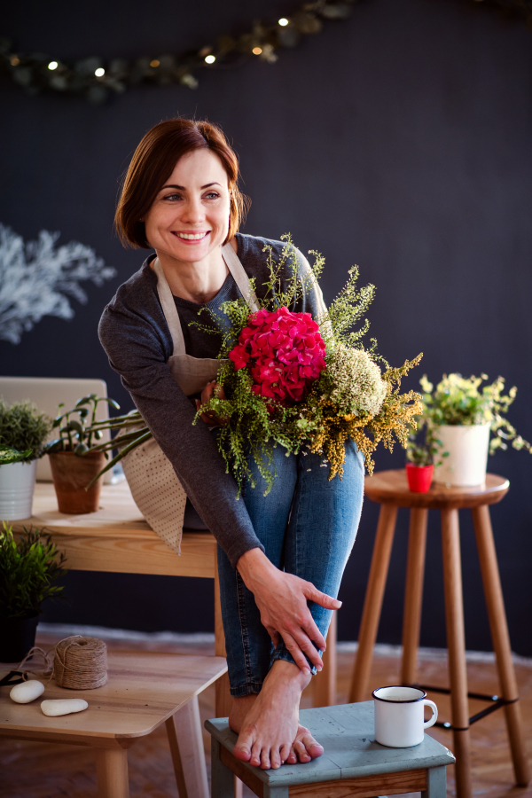 A young creative woman arranging flowers in a flower shop. A startup of florist business.