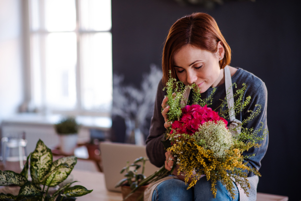 A young creative woman arranging flowers in a flower shop. A startup of florist business.