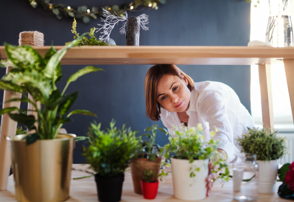 A young creative woman arranging flowers in a flower shop. A startup of florist business.