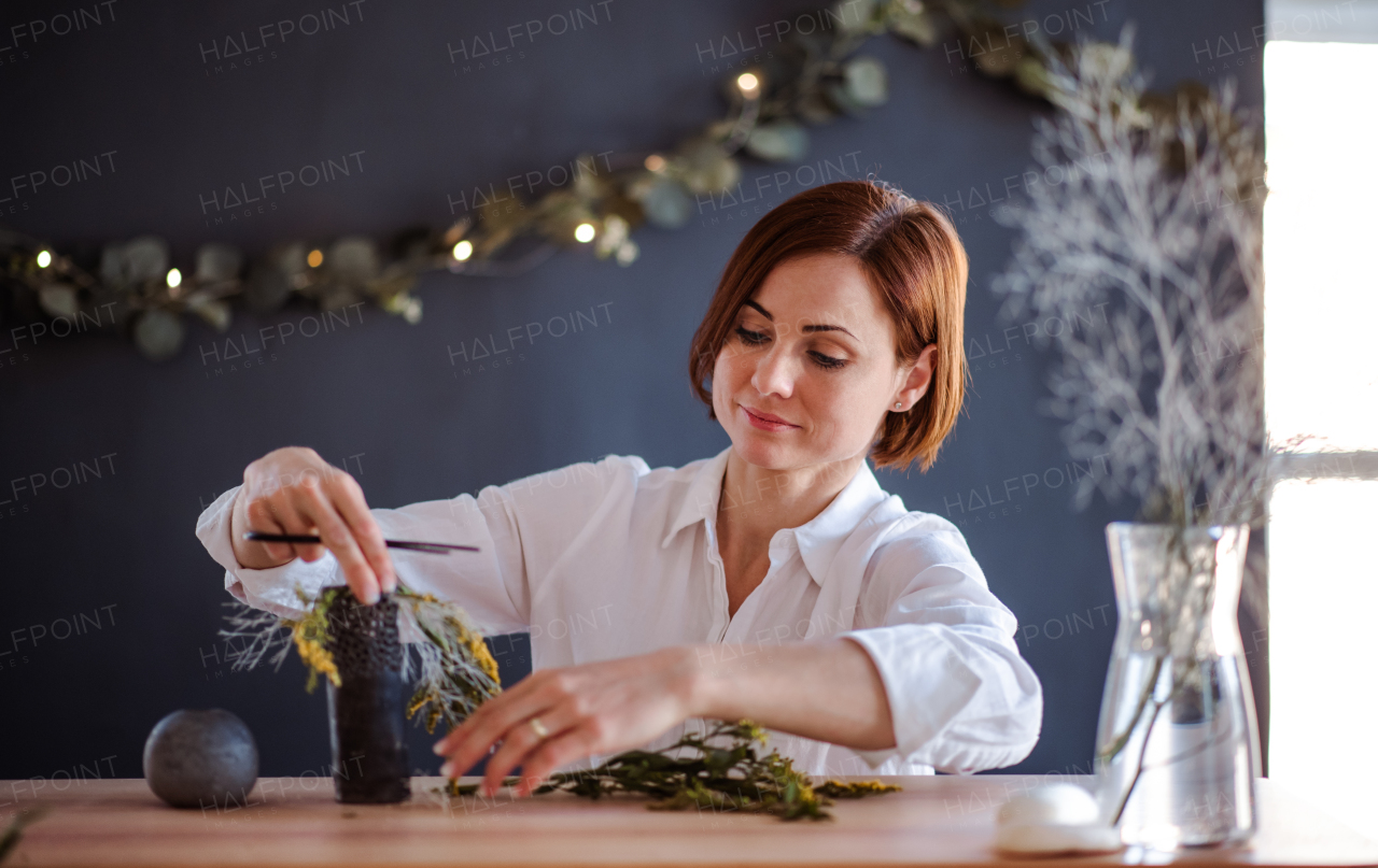 A young creative woman arranging flowers in a flower shop. A startup of florist business.