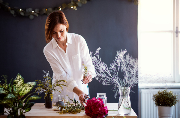 A young creative woman arranging flowers in a flower shop. A startup of florist business.