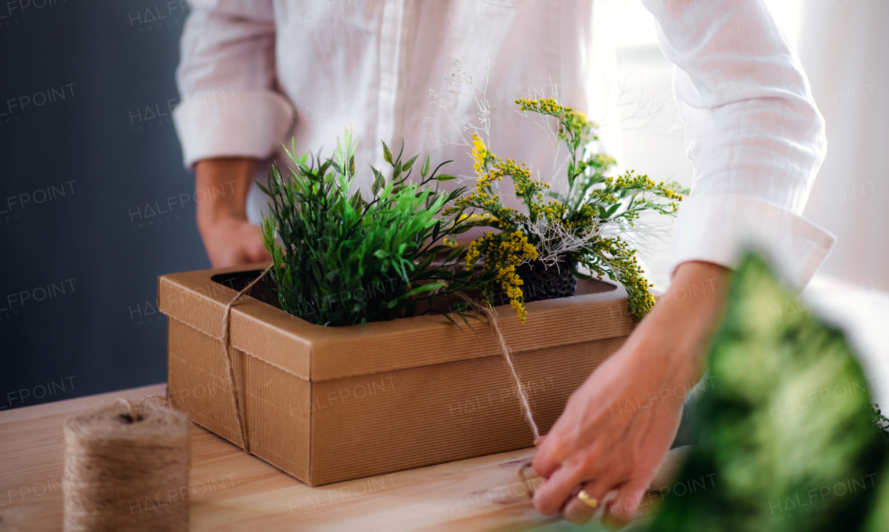 A midsection of young creative woman working in a flower shop. A startup of florist business.