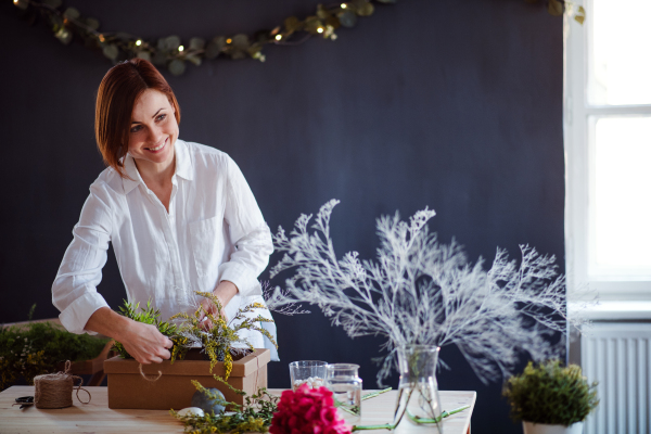 A young creative woman blogger or vlogger arranging flowers in a flower shop. A startup of florist business.