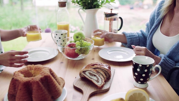 A midsection of women sitting at the table indoors, having breakfast. Slow motion.