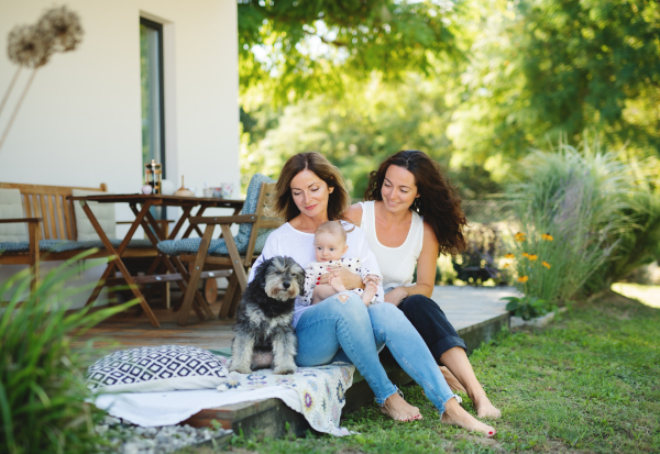 Woman with daughter and baby granddaughter resting outdoors in backyard, sitting on patio.