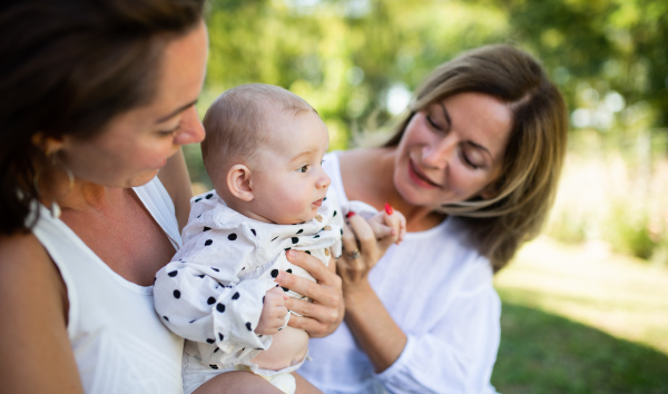 Woman with daughter and baby granddaughter resting outdoors in backyard, bonding.