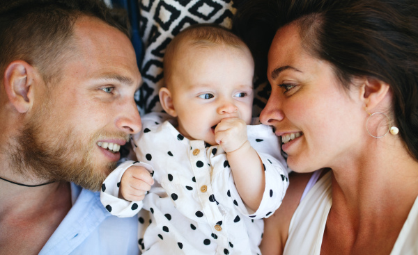 Top view of young couple with baby daughter lying on floor, close-up.