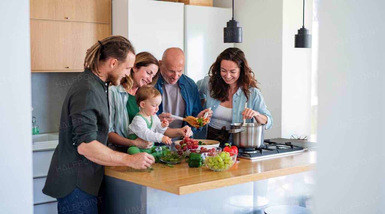 Happy multigeneration family indoors at home preparing vegetable salad in kitchen.