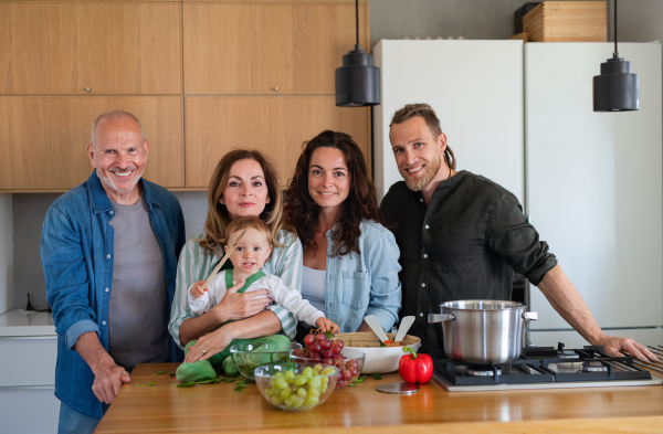 Portrait of happy multigeneration family indoors cooking at home, looking at camera.