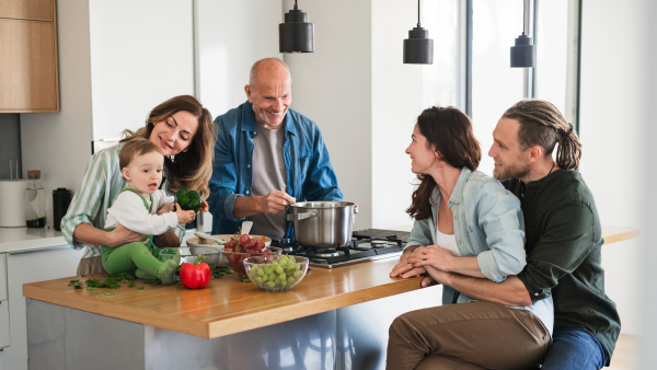 Happy multigeneration family indoors at home cooking in kitchen.