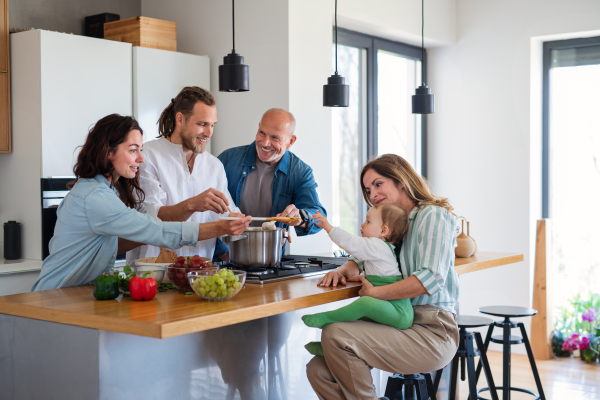 Portrait of happy multigeneration family with baby indoors at home cooking.