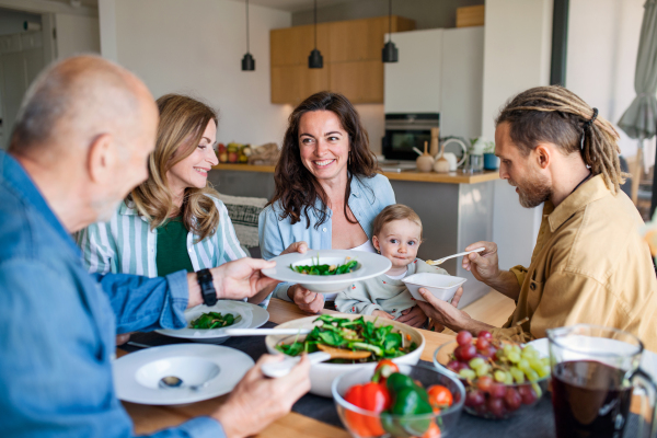 A happy multigeneration family indoors at home eating healthy lunch.