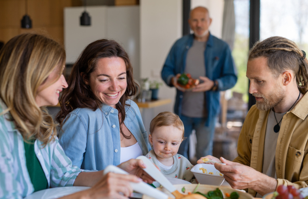 A happy multigeneration family indoors at home eating healthy lunch.