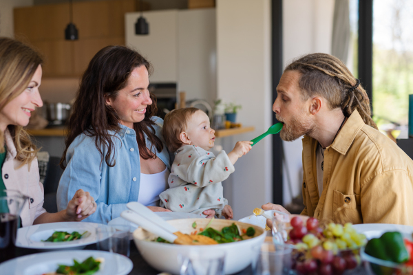 A happy multigeneration family indoors at home eating healthy lunch.