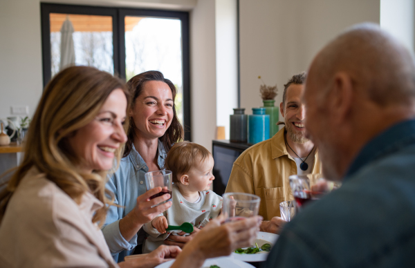 A happy multigeneration family indoors at home eating healthy lunch, having good time.