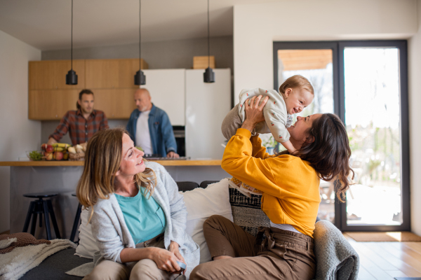 A happy multigeneration family with small baby indoors at home, visiting concept.