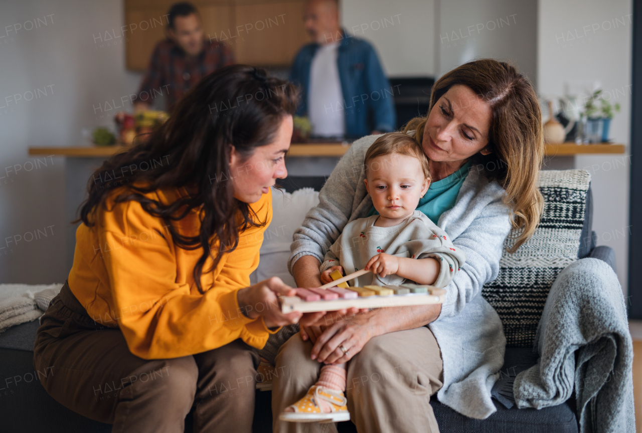 A happy multigeneration family with small baby indoors at home, visiting concept.