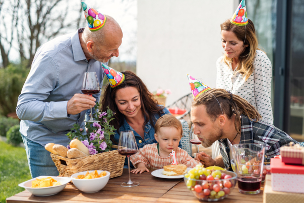 A happy multigeneration family outdoors in garden at home, birthday celebration party.