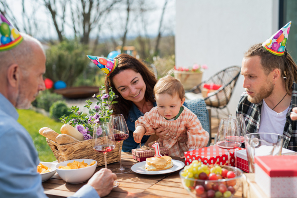 A happy multigeneration family outdoors in garden at home, birthday celebration party.