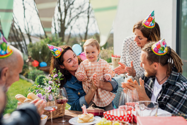 A happy multigeneration family outdoors in garden at home, birthday celebration party.