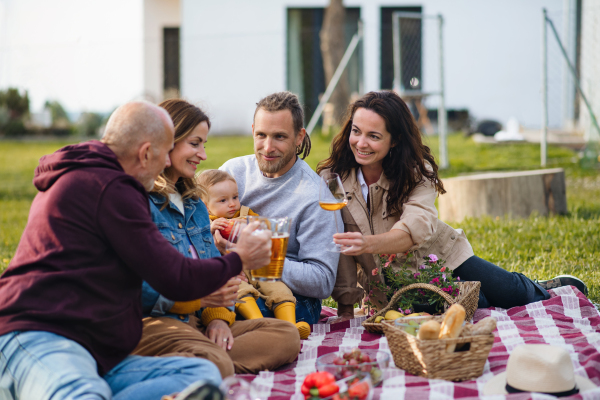 Happy multigeneration family outdoors having picnic in backyard garden, relaxing.