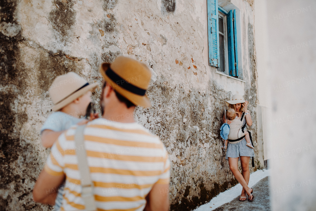 A young family with two toddler children and hats in town on summer holiday.