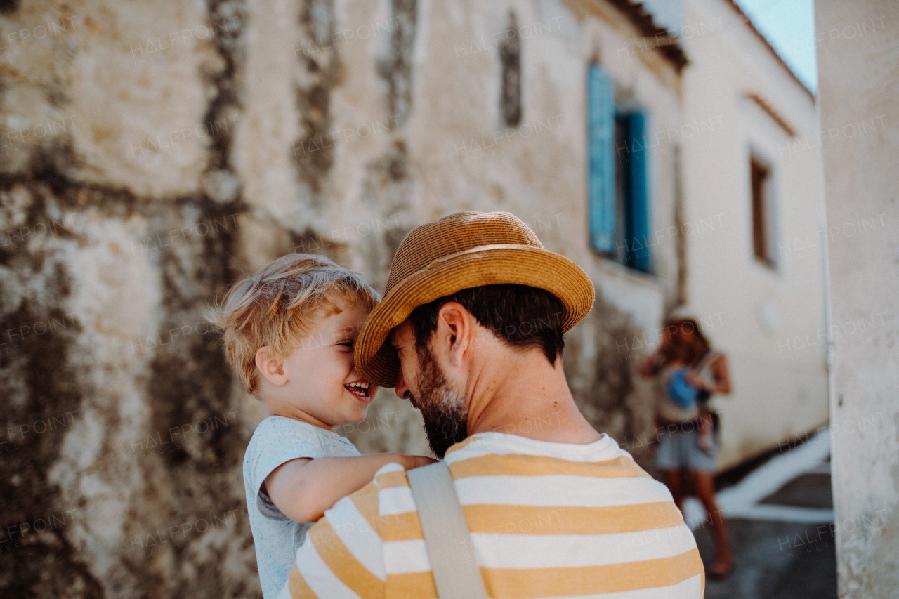 A father holding a happy toddler son in town on summer holiday.