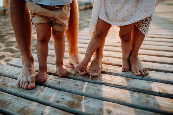 Legs and feet of family standing on beach on summer holiday, a midsection and close-up.