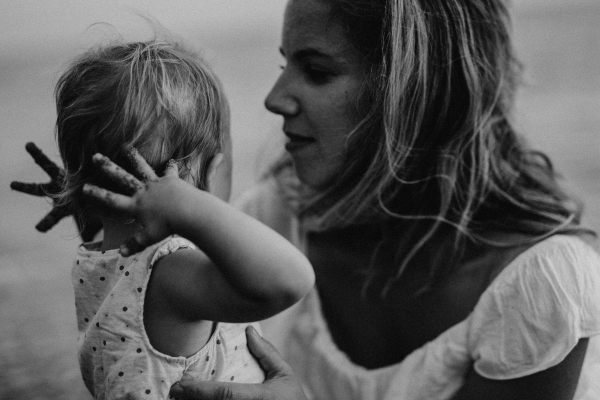 A close-up of young mother with a toddler girl on beach on summer holiday.