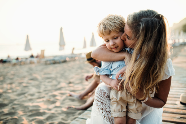 Young mother with a toddler boy having fun on beach on summer holiday. Copy space.