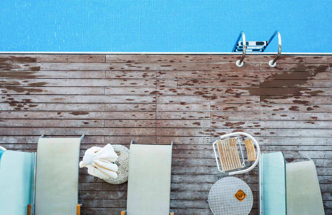 A top view of sunbathing deck and private swimming pool near beach, summer holiday concept. Copy space.