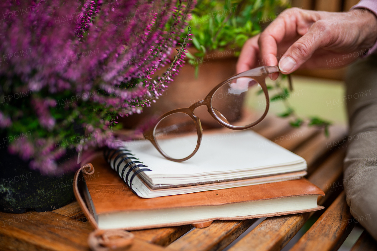 A female hand holding glasses outdoors on terrace, home office concept.