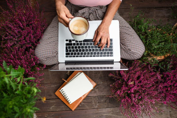 Top view of a senior woman with laptop and coffee sitting outdoors on terrace, working.