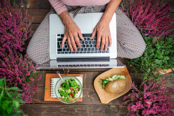 Top view of a senior woman with laptop sitting outdoors on terrace, working.