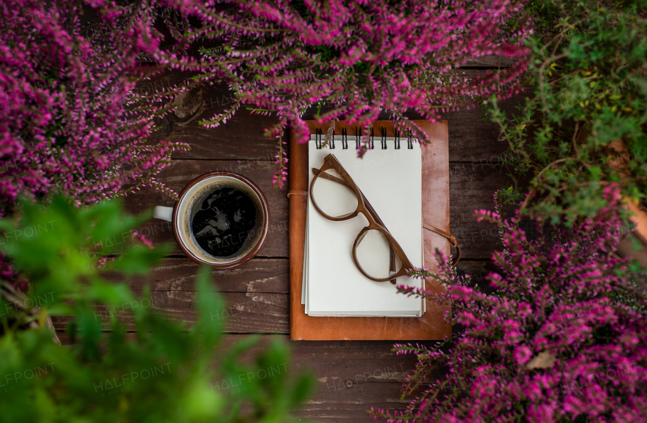 Composition of notepad, glasses and coffee on bench outdoors on terrace.