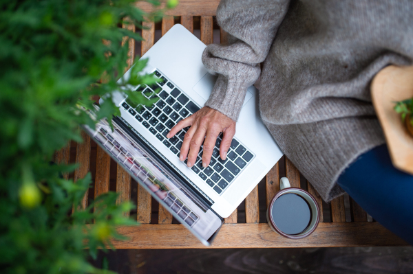 Top view of an unrecognizable senior woman with laptop sitting outdoors on terrace, working.