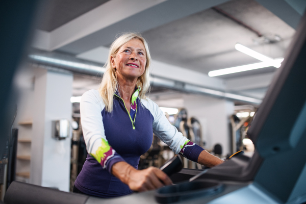 A happy senior woman in gym doing cardio work out exercise.